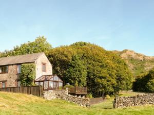 a stone house on a hill with a fence and trees at 3 Bed in Eskdale SZ502 in Eskdale