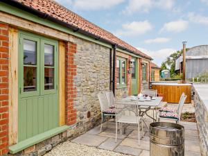 eine Terrasse mit einem Tisch und Stühlen sowie ein Gebäude in der Unterkunft 2 Bed in Taunton 80694 in North Curry