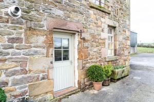 a stone building with a white door and some plants at The Hayloft at Lower Hurst Farm in Hulme End