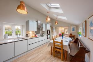 a kitchen with white cabinets and a table with chairs at The Pottage in Hoxne