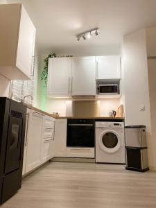- une cuisine avec des placards blancs et un lave-linge/sèche-linge dans l'établissement Charmant et moderne de L’Hay, à Chevilly-Larue