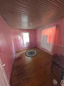 ein leeres Zimmer mit Holzboden und rosafarbenen Wänden in der Unterkunft Casa inteira Balneário Rincão in Balneário Rincão