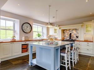 a kitchen with a large island with a clock on the wall at 4 Bed in Looe 82662 in Lanreath