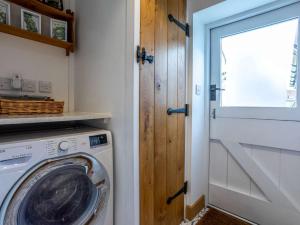 a laundry room with a washing machine and a door at 1 Bed in Axminster 82604 in Chardstock