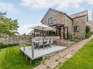 a wooden deck with a table and chairs and an umbrella at 3 Bed in Hay-on-Wye 83593 in Hay-on-Wye