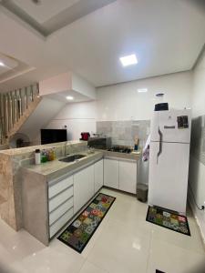 a kitchen with white cabinets and a white refrigerator at Villa dos Diamantes 35 Bahia in Porto Seguro