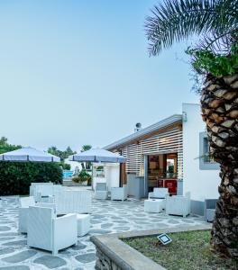 eine Terrasse mit weißen Stühlen und Sonnenschirmen in der Unterkunft Residence Il Cicero in San Giorgio