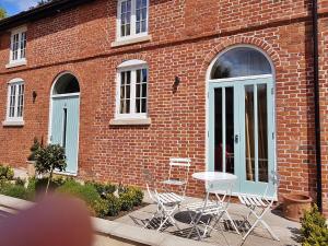 a brick building with chairs and a table in front of it at Finest Retreats - No 2 Meynell Mews in Breedon on the Hill