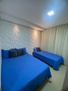 two beds in a room with blue sheets at Villa dos Diamantes 35 Bahia in Porto Seguro
