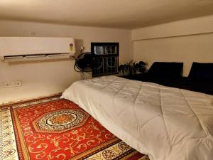 ein Schlafzimmer mit einem großen Bett und einem Teppich in der Unterkunft The Turquoise Letterbox - Loft suite at Central in Kalkutta