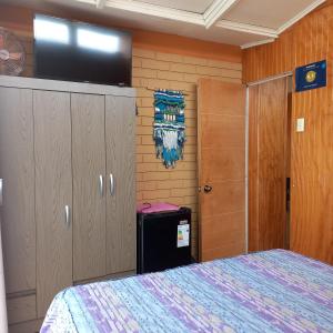 a bedroom with a bed and a flat screen tv at Hostal Los Nogales in Coquimbo