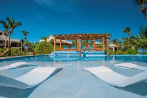 a swimming pool with white chairs and a gazebo at La Perla del Caribe - Villa Opal in San Pedro