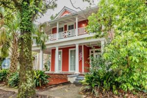 een rood huis met een witte veranda met bomen bij Pretty Peach Palace-Historic, Mins to Downtown in Mobile