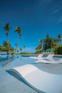 eine Gruppe von Stühlen und Palmen am Strand in der Unterkunft La Perla del Caribe - Villa Amethyst in San Pedro