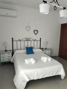 1 dormitorio con 1 cama blanca grande con almohadas azules en Vivienda turística María de Padilla, en Montiel