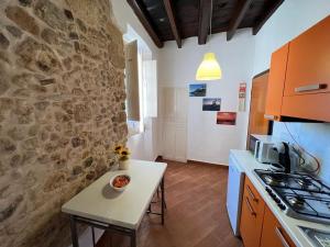 eine Küche mit einem Tisch und einer Steinmauer in der Unterkunft Casa del Bisbe in Alghero