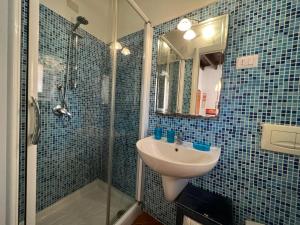 ein blau gefliestes Bad mit einem Waschbecken und einer Dusche in der Unterkunft Casa del Bisbe in Alghero