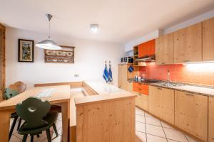 una cocina con armarios de madera, mesa y sillas en Appartamenti Cesa Maria Mountain Hospitality, en Canazei