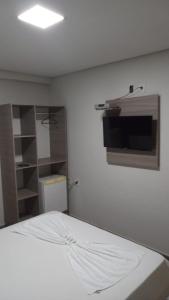 um quarto com uma cama e uma televisão na parede em POUSADA TAHITI em Pasto da Mata