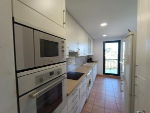 Il comprend une grande cuisine avec des placards blancs et un réfrigérateur. dans l'établissement Apartamento con solárium en Marina Sant Jordi (MSJ81), à Calafat