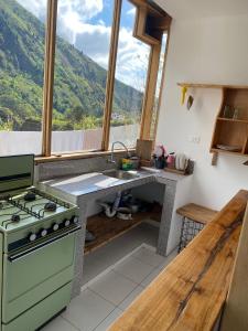 a kitchen with a stove and a sink and a window at Backpackers-balcones-river-lodge in Baños