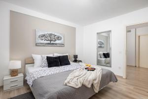 a white bedroom with a large bed and a mirror at Apartment City flower in Rijeka