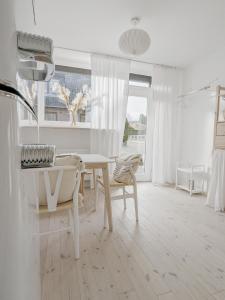 a white living room with a table and chairs at Nordic Bo - Wellen, Wald und wilde Küste in Surendorf