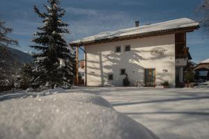 a snow covered house with a christmas tree in front of it at Residence Iris in Valdaora