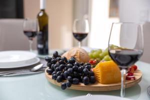 a plate of fruit and cheese and two glasses of wine at Apartment City flower in Rijeka