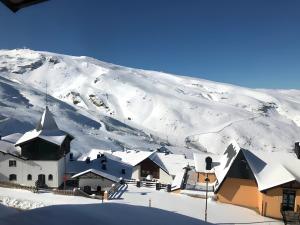 un pueblo cubierto de nieve con una montaña en el fondo en Apartamento Zona Alta Sierra Nevada, en Sierra Nevada