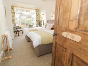 Un dormitorio con 2 camas y una puerta con un cartel. en Cedar Gardens en Llabedr-Dyffryn-Clwyd