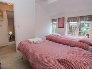 drie bedden in een kamer met rode en witte lakens bij The Little White Cottage in Chipping Norton