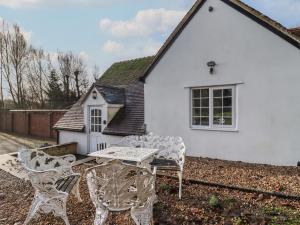 een tafel en stoelen voor een wit huis bij The Little White Cottage in Chipping Norton