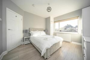 a white bedroom with a bed and a window at Enjoy a Luxury & Peaceful Home in Loughton, Essex in Loughton