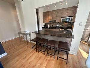 a kitchen with a bar with four stools at River North Hideaway with Amazing Views and Parking in Chicago
