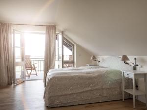 um quarto branco com uma cama e uma varanda em Ferienwohnung mit Kamin im Gut Ulrichshusen em Tressow