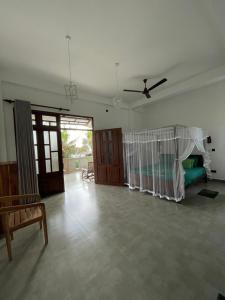 a living room with a bed and a ceiling fan at Plantation Surf Inn & Restaurant in Midigama