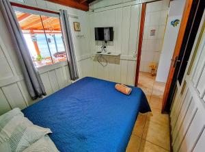 um pequeno quarto com uma cama azul e uma janela em Casa charmosa pé na areia por do sol em Florianópolis