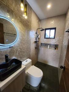a bathroom with a toilet and a sink and a mirror at 4 bedrooms Newly Build Vacation House in Bacolod