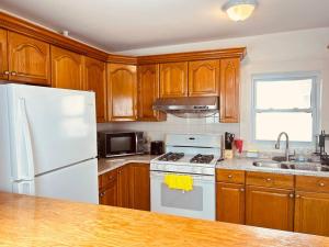 a kitchen with wooden cabinets and a white refrigerator at 17 Cozy&Spacious 3 bedroom home in Malden in Malden