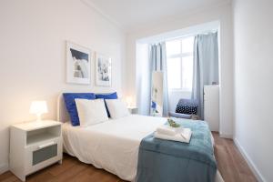 een slaapkamer met een groot wit bed met blauwe accenten bij BmyGuest - Boa Hora Apartment in Lissabon