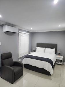a bedroom with a large bed and a chair at Vusi's Guesthouse in Durban