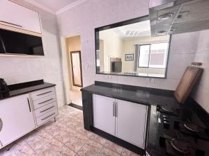 uma grande cozinha com armários brancos e um grande espelho em Apartamento Temporada Guarujá no Guarujá