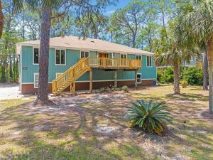 a green house with a porch and a deck at 086 DI Big House - 6 Bedrooms in Dauphin Island