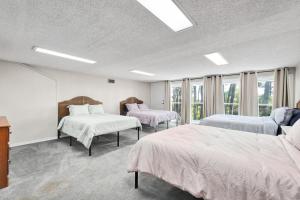 two beds in a room with windows and two bedsitures at 086 DI Big House - 6 Bedrooms in Dauphin Island