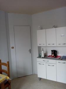 a kitchen with white cabinets and a table and a door at Studio des Thermes 2* in Vittel