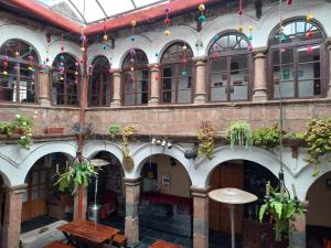 a large building with tables and potted plants at Pirwa Backpackers Colonial in Cusco