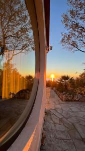 a view of the sunset through a circular window at Le chardonneret élégant in Kanali