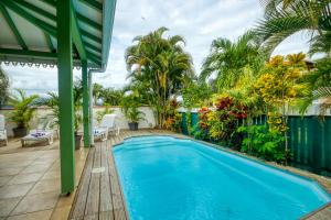 a swimming pool on a patio with palm trees at Villa avec piscine MQTI14 in Les Trois-Îlets