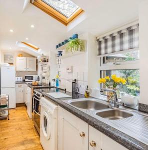 a kitchen with white cabinets and a sink and a window at Juliet Cottage, late Georgian treasure, charming, cosy and historic, only a short walk to Alnwick Castle in Alnwick